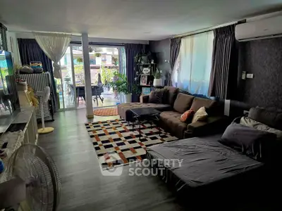 Spacious living room with modern decor and large windows opening to a balcony, perfect for relaxation.