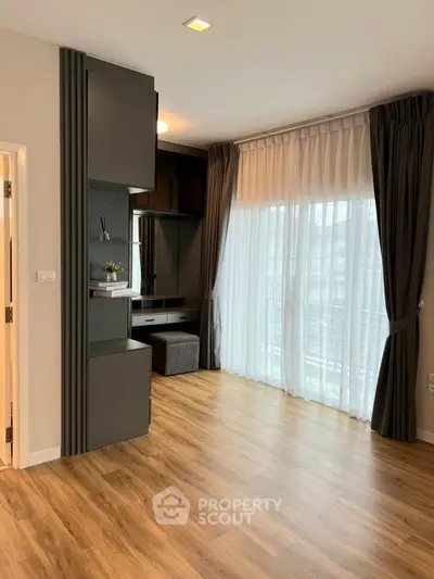 Spacious modern living room with elegant wooden flooring and large window drapes.