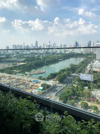 Stunning cityscape view from a high-rise balcony overlooking lush greenery and urban skyline.