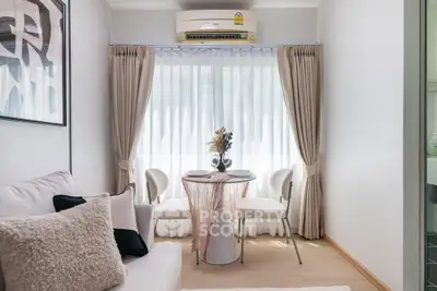 Cozy living room with elegant decor and natural light, featuring a small dining area and air conditioning.