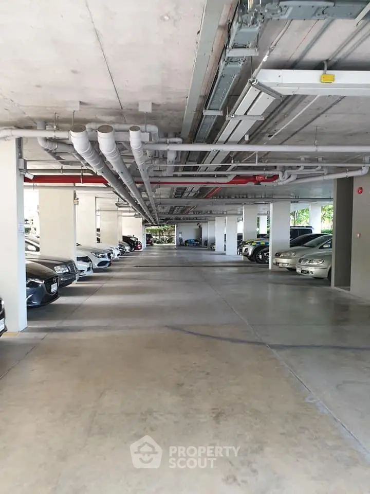 Spacious underground parking area with multiple parked cars and visible piping.
