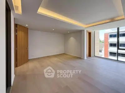 Spacious modern living room with wooden flooring and large windows in a contemporary apartment.