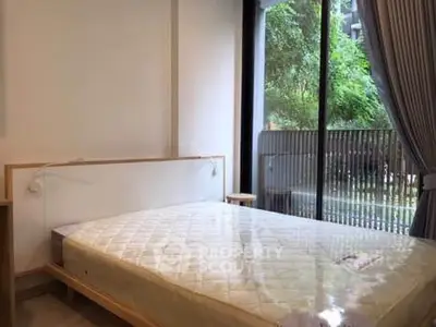 Spacious bedroom with large window and garden view, featuring a minimalist bed frame and elegant curtains.