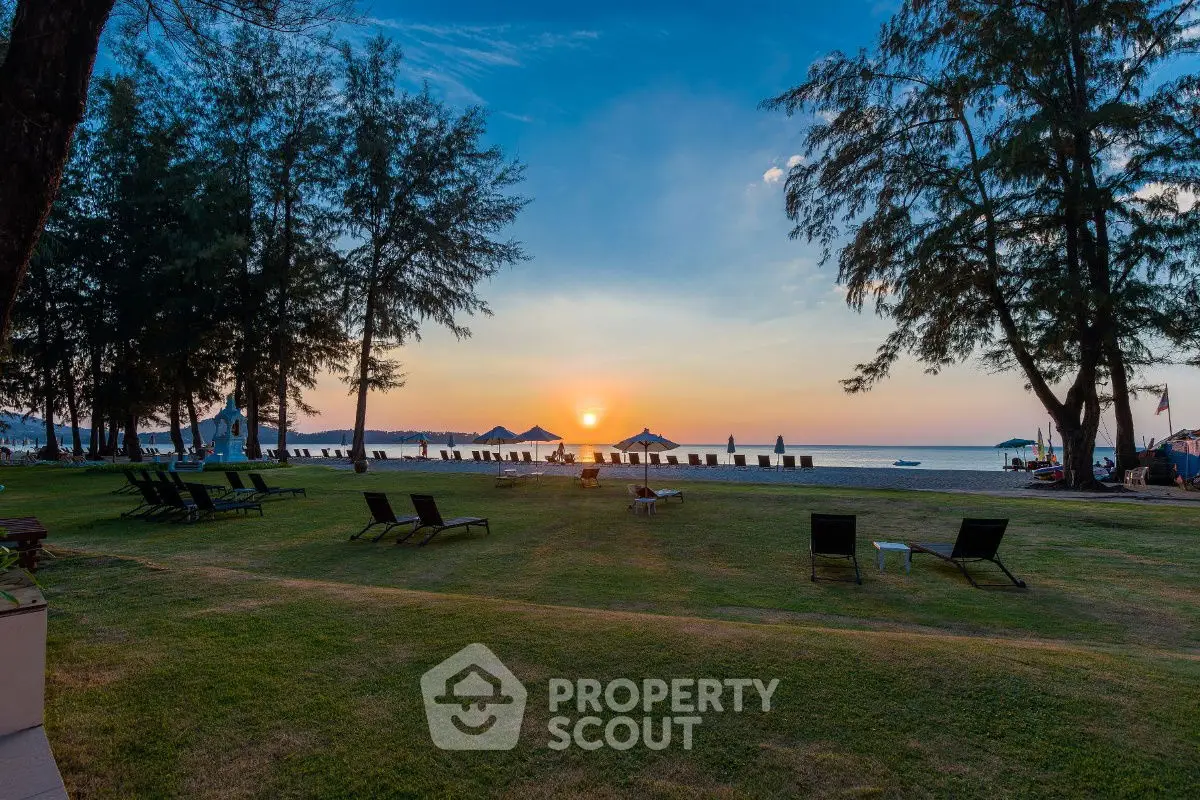 Stunning beachfront view with sunset over the ocean and lush greenery.