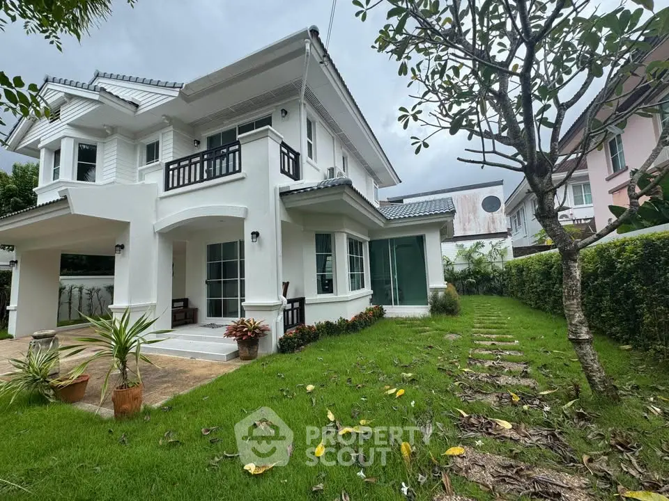 Charming two-story white house with lush green lawn and inviting porch in a serene neighborhood.
