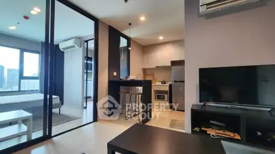 Modern open-plan living room with kitchen and city view, featuring sleek furniture and large windows.