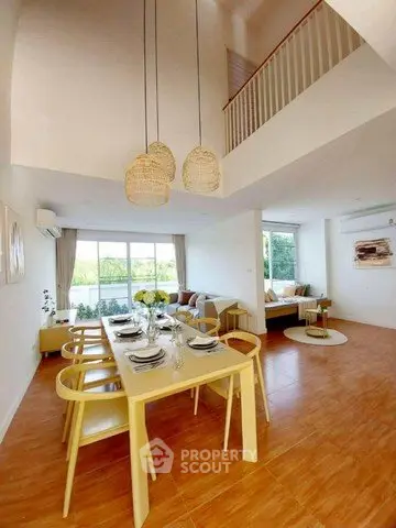 Spacious modern living room with high ceiling and elegant dining area, featuring large windows and stylish decor.