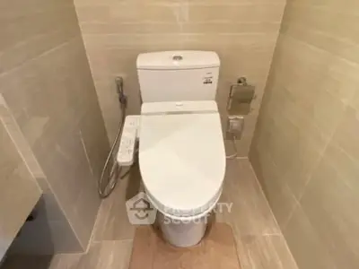 Modern bathroom with sleek toilet and beige tiled walls.