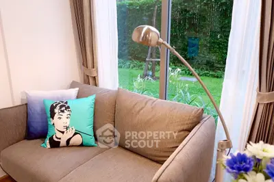 Cozy living room with stylish decor and garden view through large window.