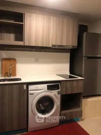 Modern kitchen with washing machine and sleek cabinetry in compact layout.