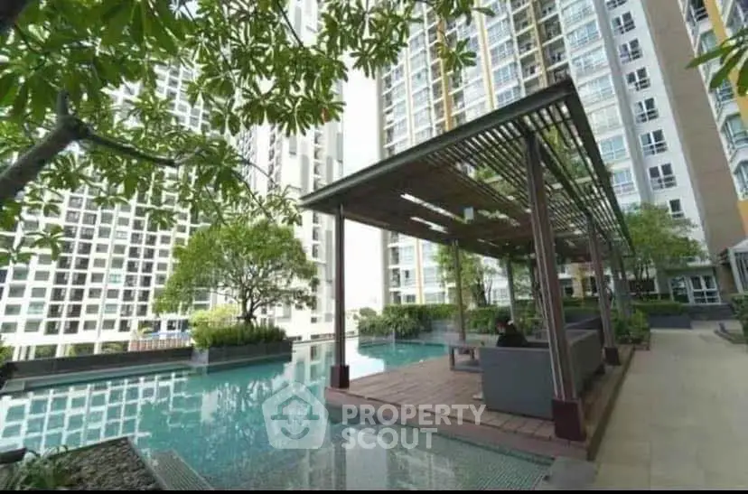 Luxurious condominium pool area with modern seating and lush greenery