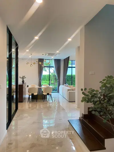 Luxurious open-plan living and dining area with elegant decor and large windows overlooking a lush garden.