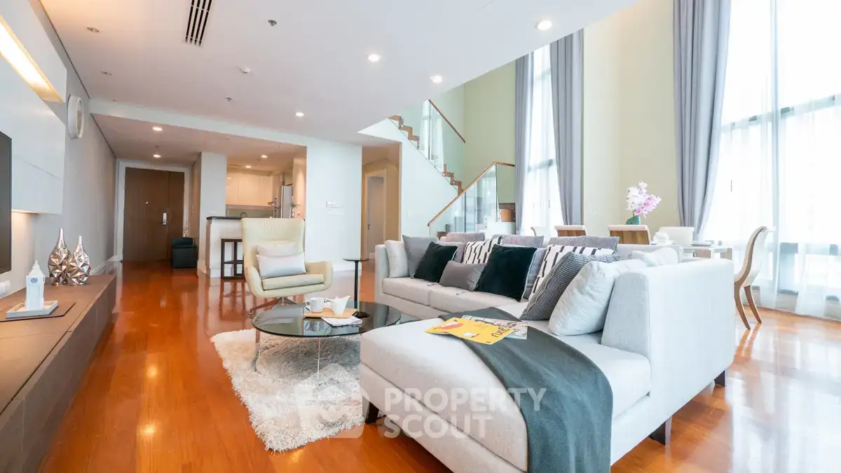Luxurious open-plan living room with modern decor and elegant staircase in a spacious apartment.