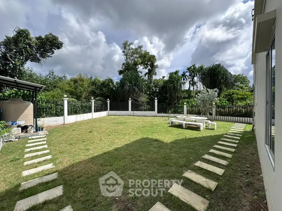 Spacious backyard with lush greenery and outdoor seating area, perfect for relaxation and entertainment.