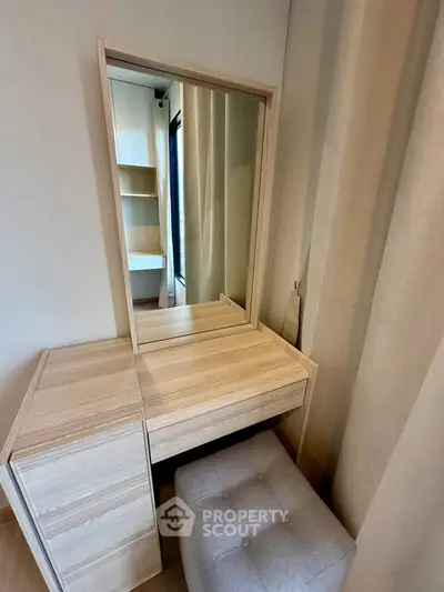 Elegant bedroom vanity with mirror and cushioned stool in modern apartment