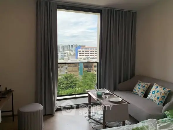 Cozy living room with city view through large window, modern decor and comfortable seating.