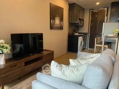 Modern living room with cozy sofa, TV, and compact kitchen area.