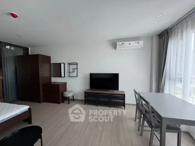 Modern studio apartment with sleek furniture and large windows offering natural light.