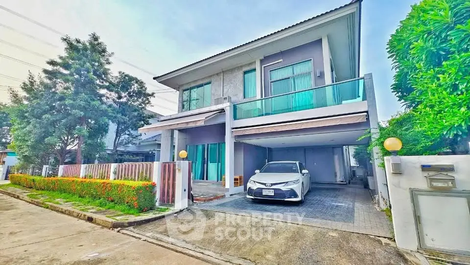Modern two-story house with carport and lush greenery in a suburban neighborhood.