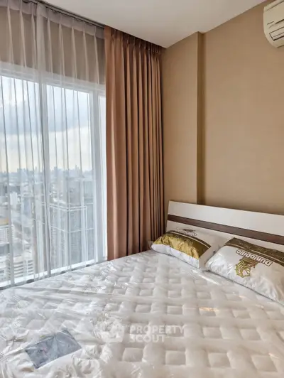 Modern bedroom with city view, featuring a large window and stylish decor in a high-rise apartment.
