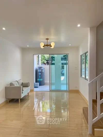 Spacious living room with modern lighting and large windows opening to a balcony, perfect for natural light.