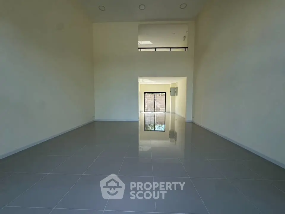 Spacious empty room with high ceiling and large windows, perfect for customization.