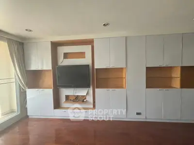 Spacious living room with built-in TV unit and wooden flooring