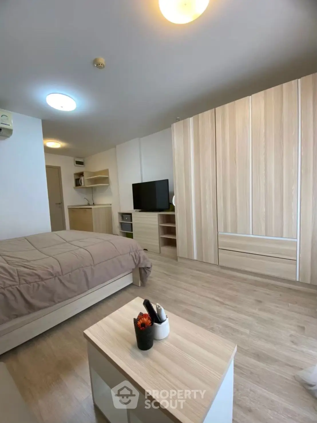 Modern studio apartment with cozy wooden furnishings and a sleek TV setup.
