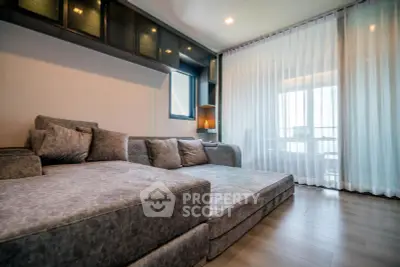 Spacious modern living room with large sofa and floor-to-ceiling windows.