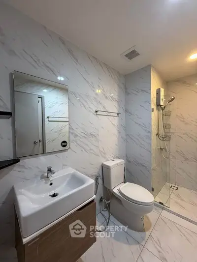 Modern bathroom with sleek design, featuring a glass shower and elegant fixtures.