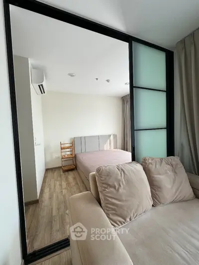 Modern apartment with cozy living room and bedroom, featuring sliding glass partition and stylish decor.