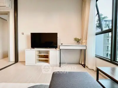 Modern living room with sleek TV stand and large windows offering natural light.