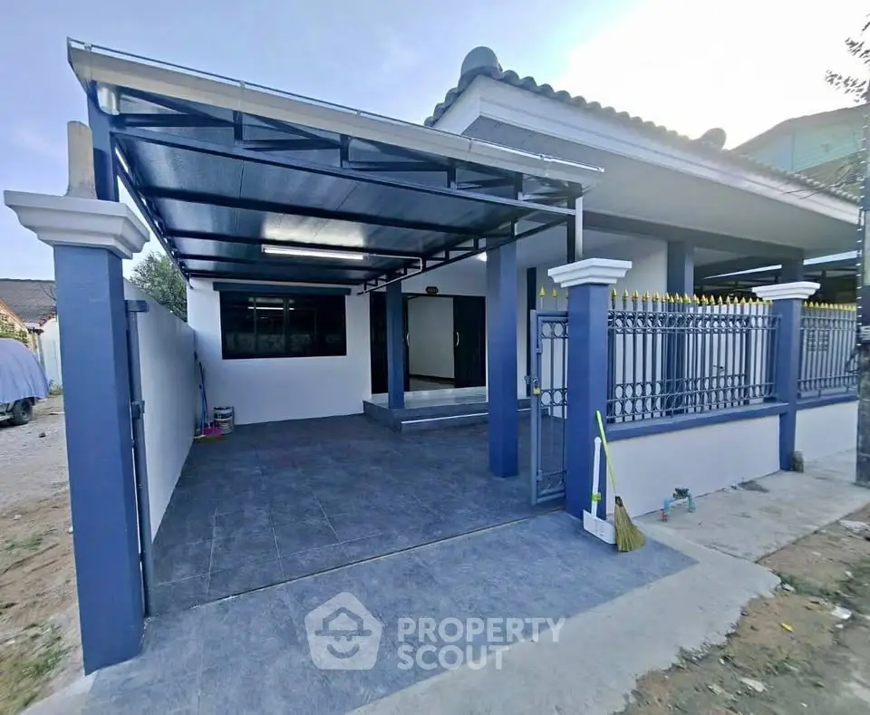 Modern blue and white house exterior with covered carport and gated entrance.