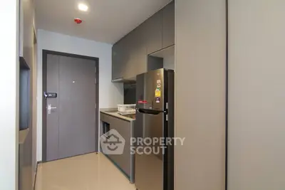 Modern compact kitchen with sleek cabinetry and stainless steel appliances in a contemporary apartment.