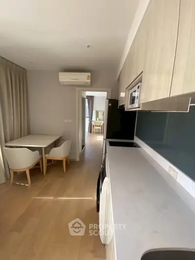 Modern kitchen with sleek design and dining area in open layout apartment.