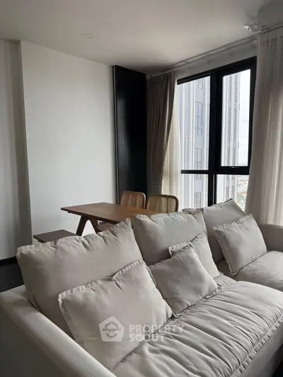 Modern living room with cozy sofa and dining area, featuring large windows with city view.