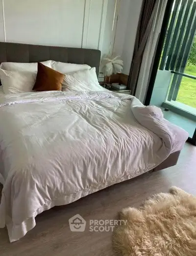 Cozy bedroom with plush bedding and balcony view, perfect for relaxation.