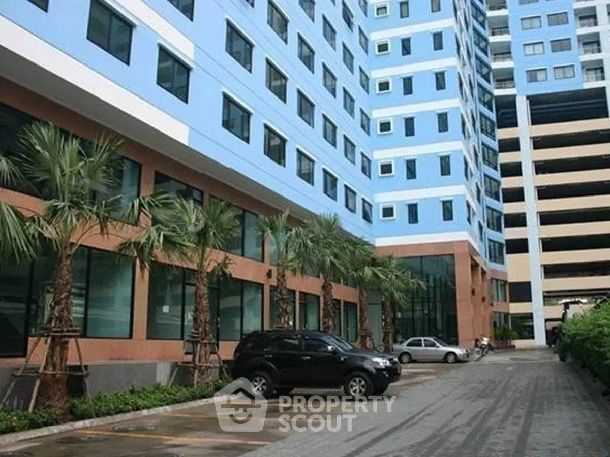 Modern residential building with parking area and palm trees, showcasing urban living.