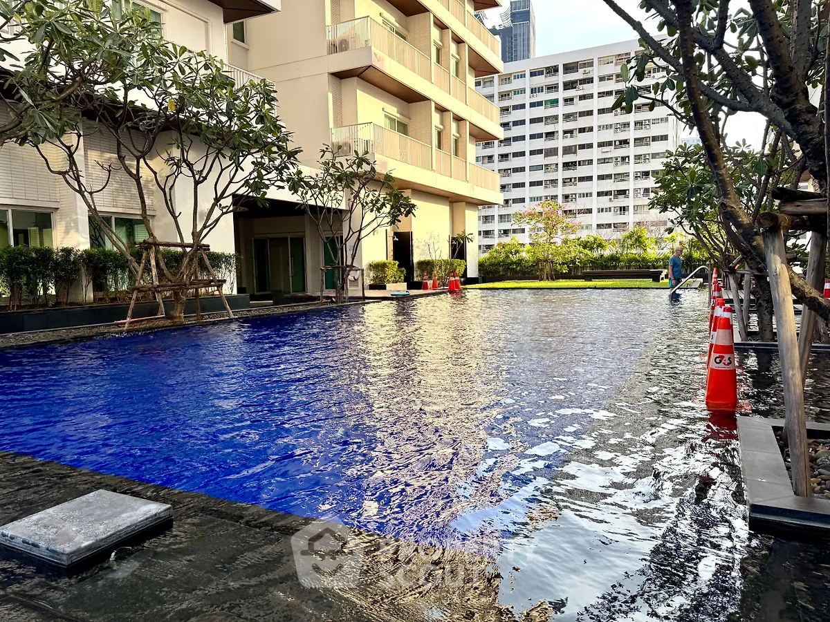 Luxurious residential building with a serene outdoor pool and lush greenery, perfect for relaxation and leisure.