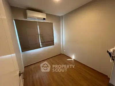 Cozy unfurnished bedroom with wooden flooring and air conditioning, perfect for personalization.