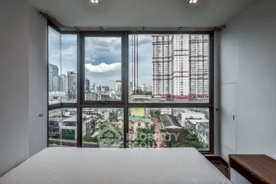 Stunning city view from modern bedroom with large windows in high-rise apartment.