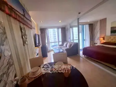 Modern open-plan living room with dining area and cozy bedroom in a stylish apartment.