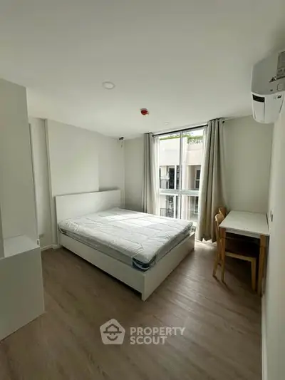 Modern bedroom with large window and minimalist furniture in a bright apartment.