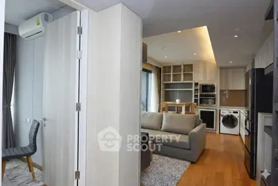 Modern open-plan living room with kitchen, featuring cozy sofa and built-in appliances.