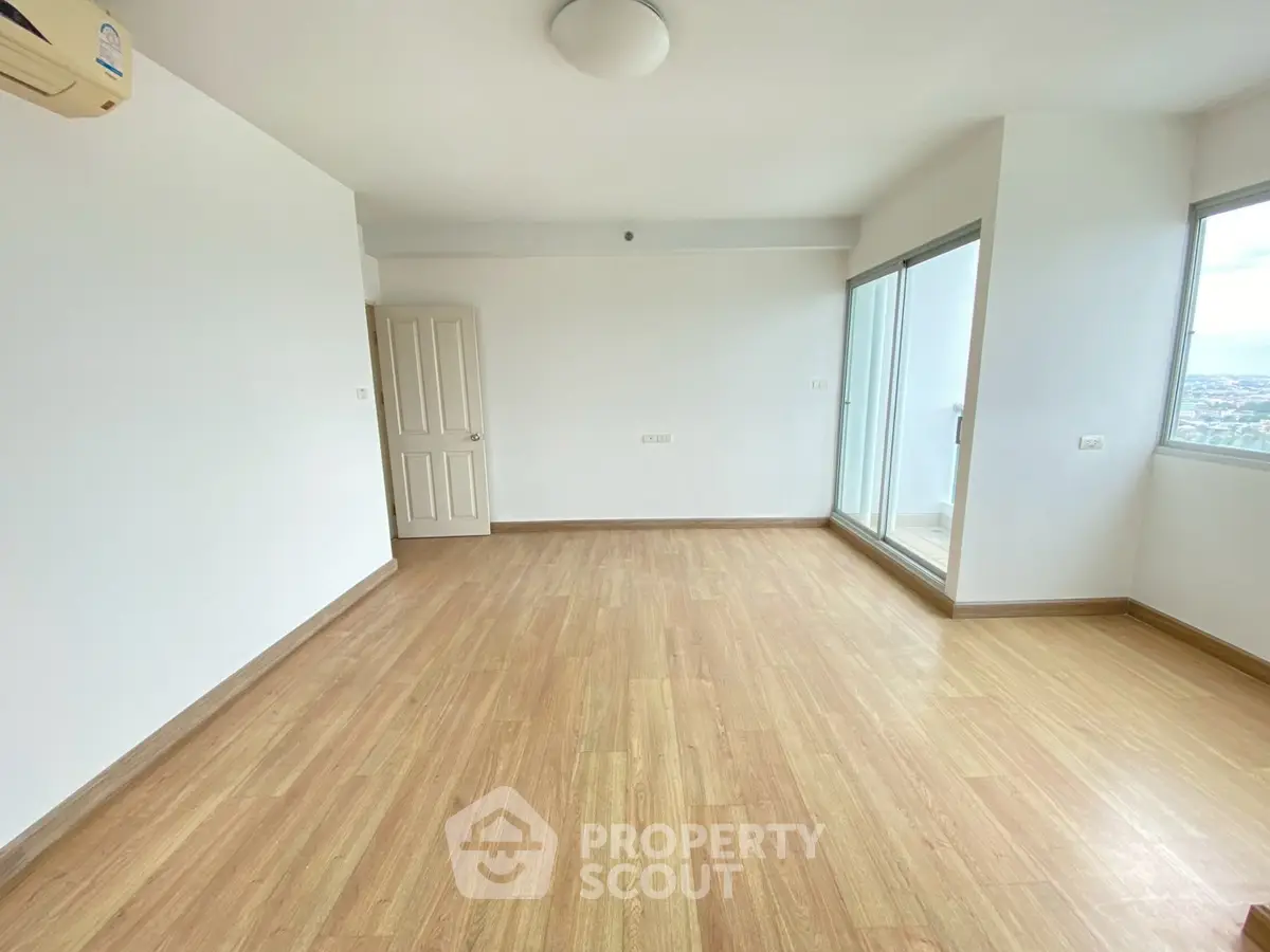 Spacious empty living room with wooden flooring and balcony access