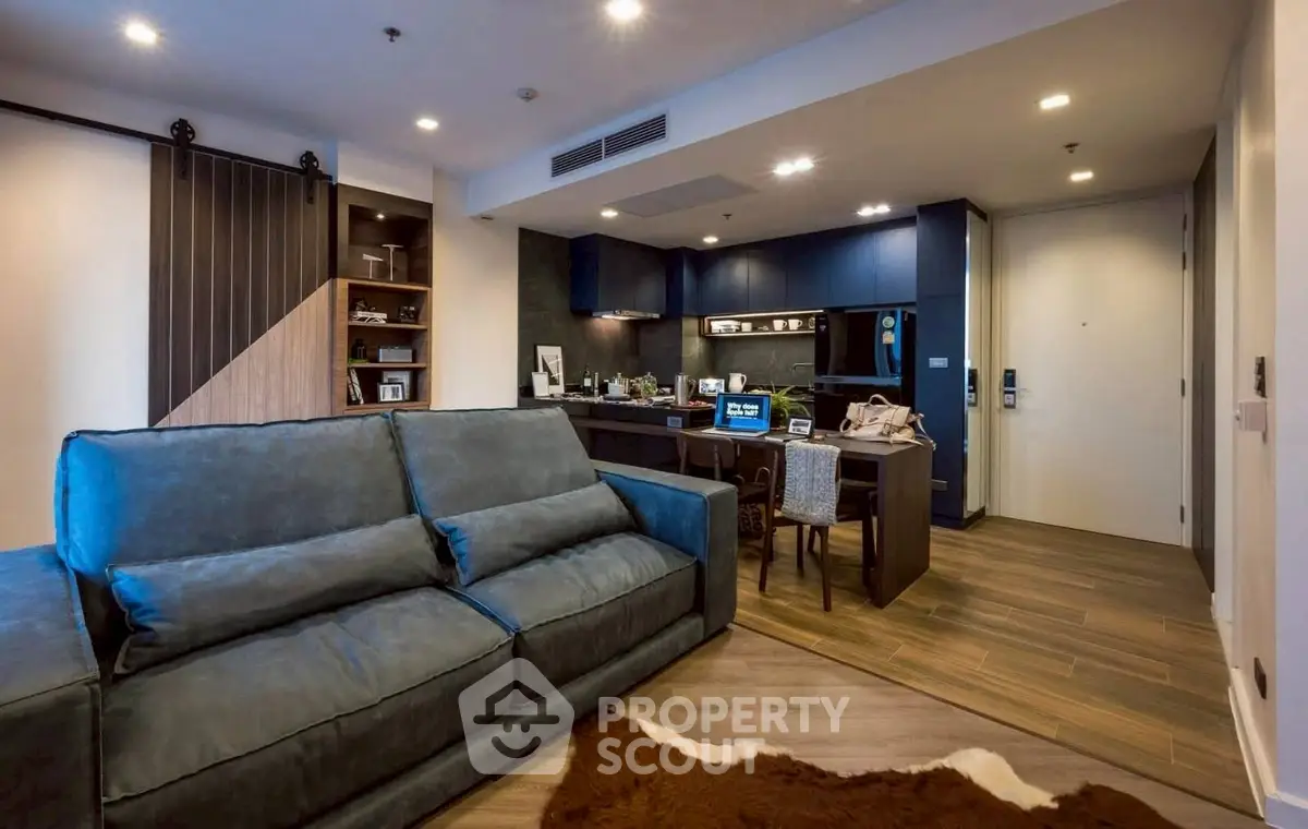 Modern living room with stylish blue sofa and cozy workspace in open layout apartment.