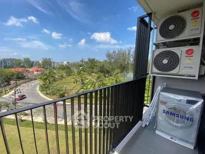 Scenic balcony view with air conditioning units overlooking lush park and road.