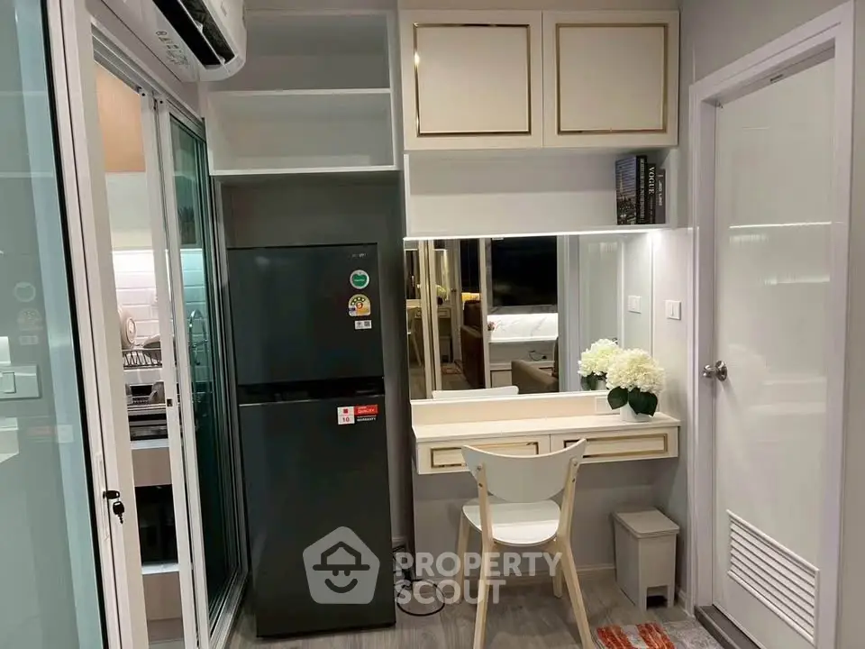 Modern compact kitchen with sleek fridge and stylish vanity area in a cozy apartment.