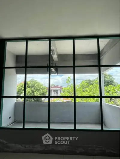 Spacious balcony with large windows offering lush green views