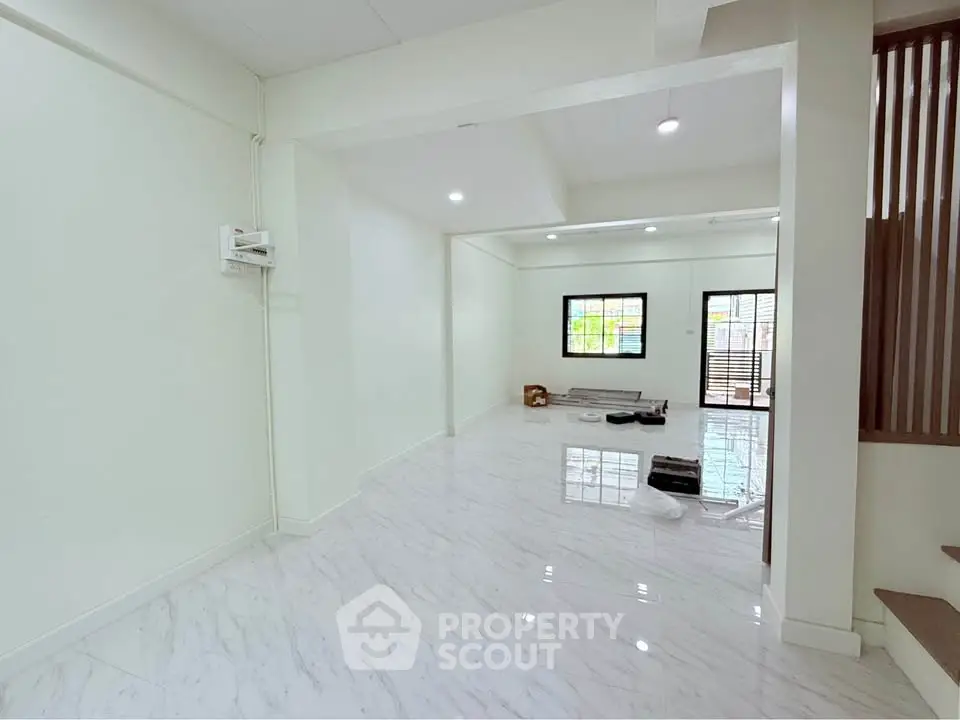 Spacious open-plan living area with glossy marble floors and natural light.